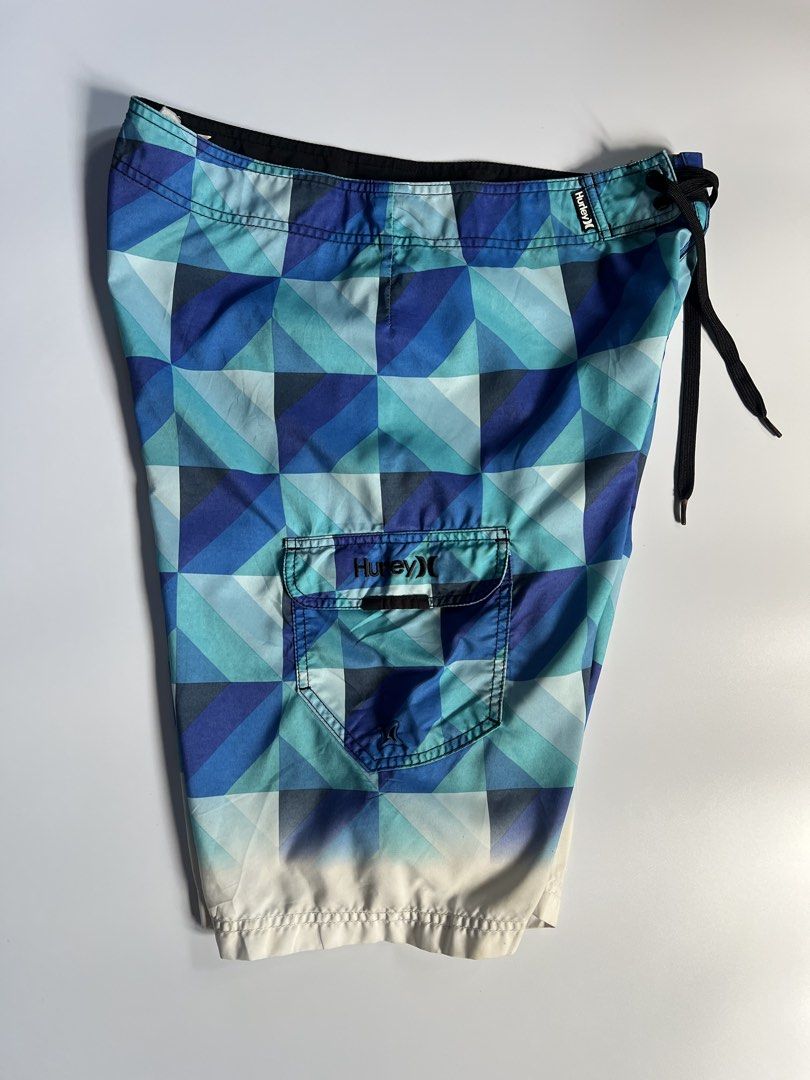 Hurley Geometric Print Board Shorts Blue (Category: Swim Trunks & Board Shorts) located in Baler. Submitted by allthrifted31 (Listing ID 1462962890, Image 3). Description: - Cool Hurley board shorts - Geometric pattern in shades of blue and teal - Side cargo pocket with velcro closure - Drawstring waist for adjustable fit - Ideal for beach or pool activities.