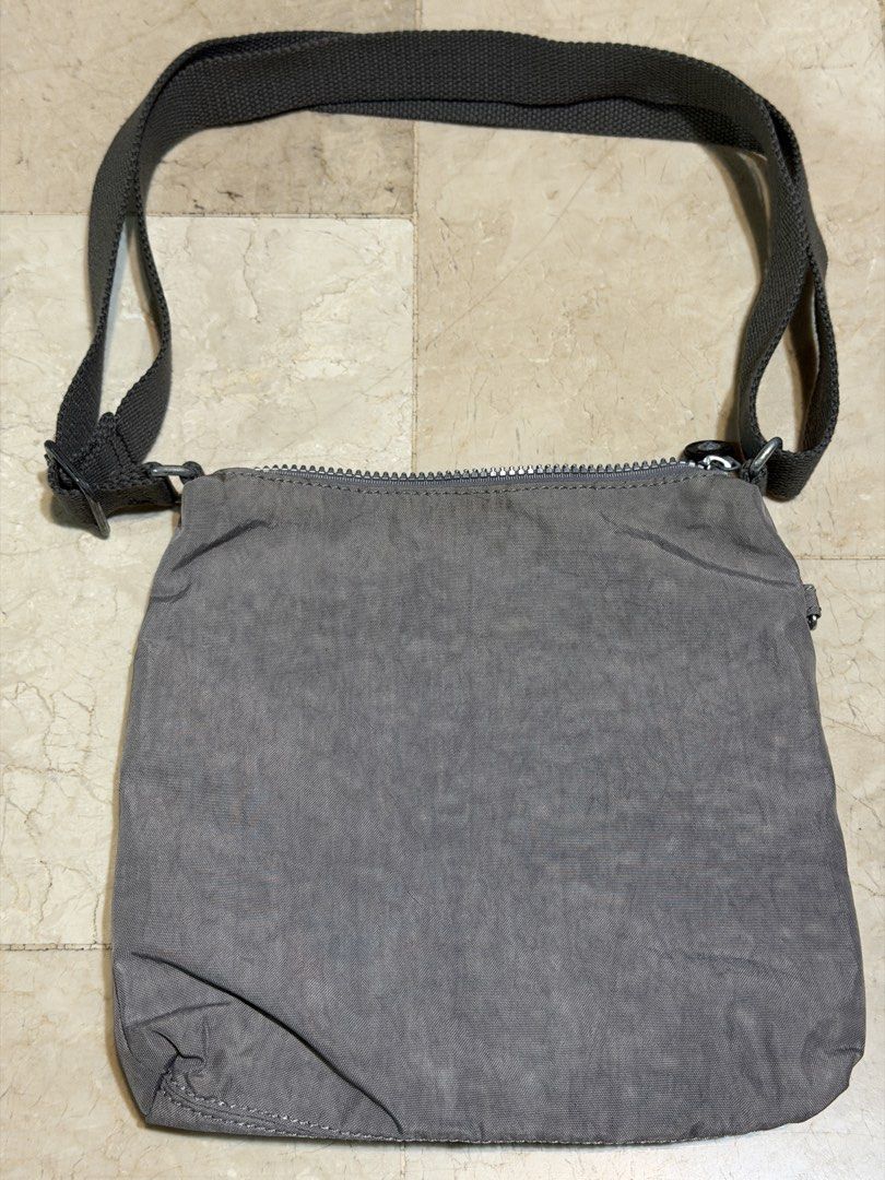 Kipling Grey Nylon Crossbody Bag with Monkey Charm (Category: Cross-body Bags) located in Manila. Submitted by db_collective (Listing ID 1462987089, Image 2). Description: - Grey Kipling crossbody bag - Durable nylon material - Front zipper pocket - Main zipper compartment - Adjustable strap for comfort - Includes signature Kipling monkey charm - Ideal for everyday use - Shows some signs of wear, especially around zipper areas and hardware Please