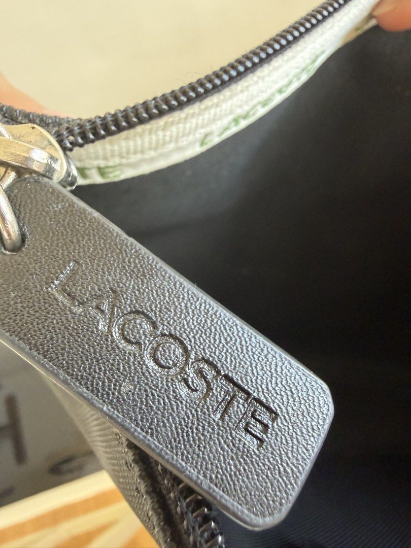 Lacoste Black Pouch with Crocodile Logo (Category: Purses & Pouches) located in Bacolor. Submitted by ieshaaa.1 (Listing ID 1462893005, Image 2). Description: - Authentic Black Lacoste Pouch - Signature Crocodile Logo on Front - Secure Zipper Closure with Leather Pull Tab - Interior Lacoste Branding and Product Tag - Ideal for Organizing Essentials.