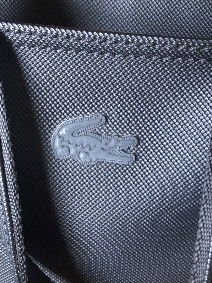 Lacoste Dark Blue-Black Textured Tote Bag (Category: Tote Bags) located in Makati City. Submitted by mitchi_koy28 (Listing ID 1462932598, Image 3). Description: - Classic blue-black Lacoste tote bag - Durable textured material - Spacious interior with zippered pocket - Comfortable shoulder straps - Ideal for everyday use or travel - Simple and functional design - Original bought in store Dimension: Height 12’’ Length 15” Width 4” (top) 6”(bottom)