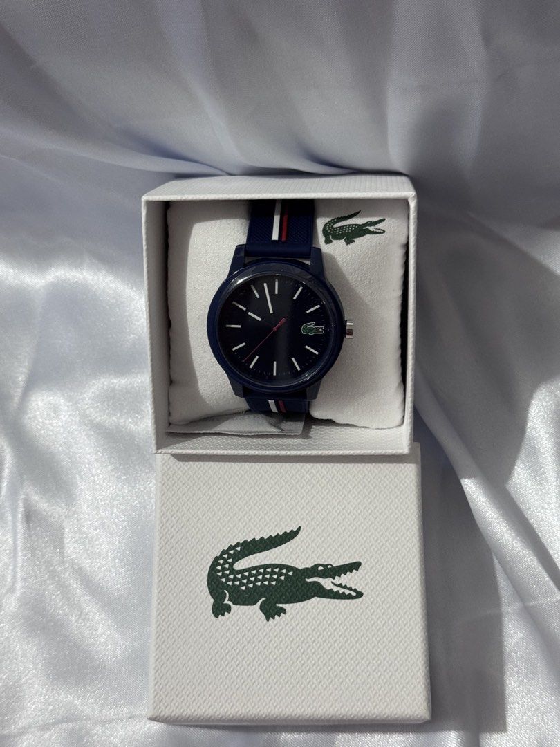Lacoste Watch with Box (Category: Women's Watches) located in Tarlac. Submitted by touchedbytash (Listing ID 1462891007, Image 1). Description: - Navy blue Lacoste watch - Comes with original box featuring iconic crocodile logo - Dark blue watch face - Matching navy blue strap with white and red stripes - Ideal for everyday wear - Great gift idea - Box interior lid also has a smaller crocodile logo.