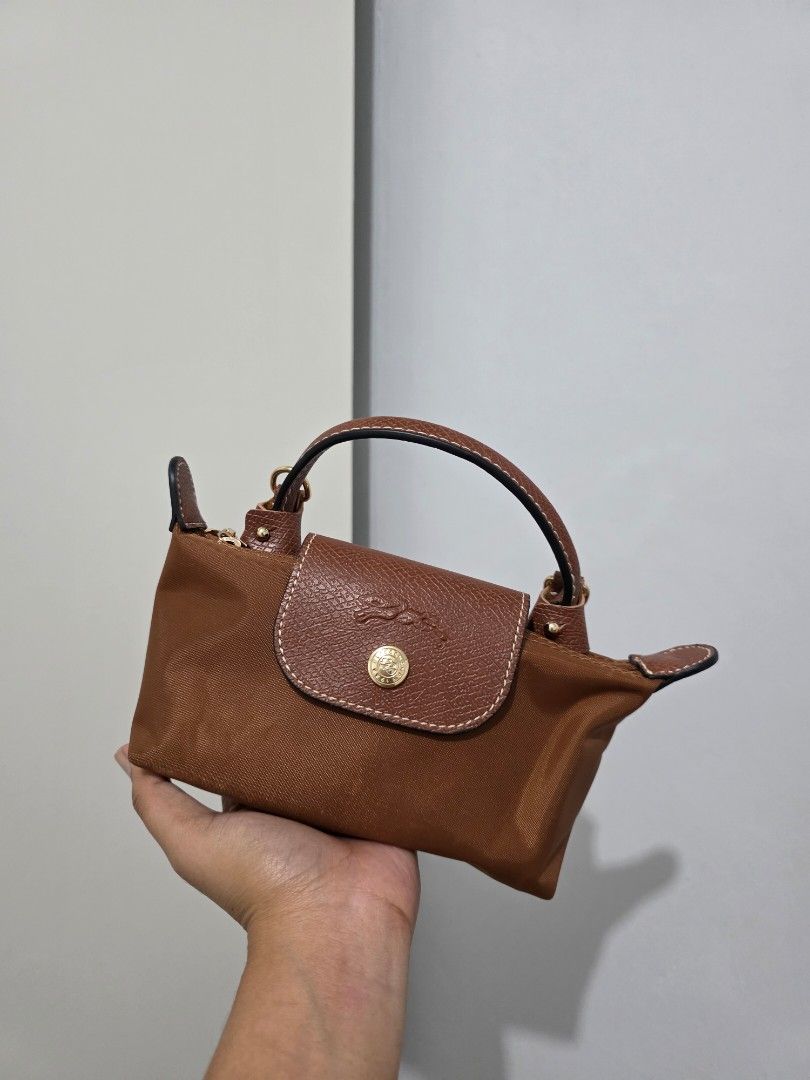 Longchamp Le Pliage Mini in Ebony (Category: Luxury Bags & Wallets) located in Manila. Submitted by decluttaro (Listing ID 1463075550, Image 2). Description: Brown Longchamp handbag. Small size, great for essentials. Leather trim and handles. Detachable shoulder strap included. Zipper closure. Gold hardware details. Very practical and stylish..
