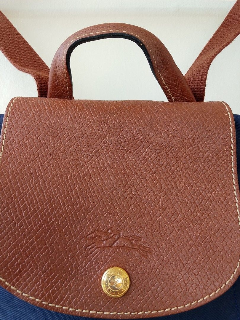 Longchamp mini "Le Pliage" Backpack (Category: Luxury Bags & Wallets) located in Taytay. Submitted by elegant.revival (Listing ID 1463051293, Image 3). Description: Materials: Features the classic lightweight, durable polyamide nylon canvas paired with textured Russian brown leather trim, top handle, and flap closure. Straps: Comes with two adjustable, webbed textile shoulder straps.Signature Detail: Accentuated with gold-tone hardware, including
