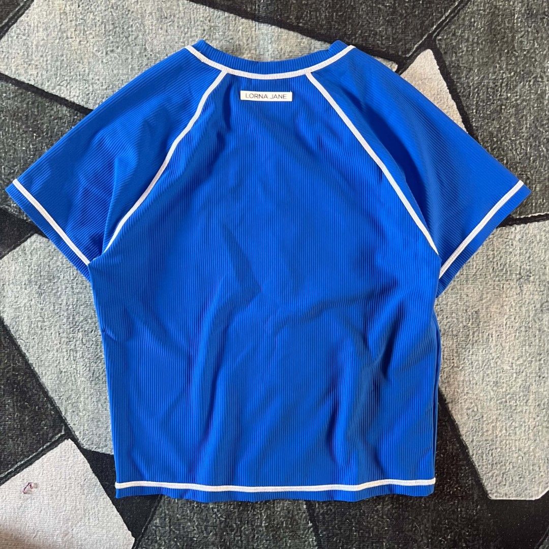 Lorna Jane Blue Ribbed Athletic top (Category: Activewear) located in Cebu City. Submitted by royalwolf-2a85 (Listing ID 1462969919, Image 3). Description: - Brand: Lorna Jane - Color: Blue - Size: XXL - width 18 - length 21 - like New - no issue - Features: Ribbed texture, white piping details, short sleeves, crew neck - Versatile: Great for workouts or casual wear - Origin: Made in China.