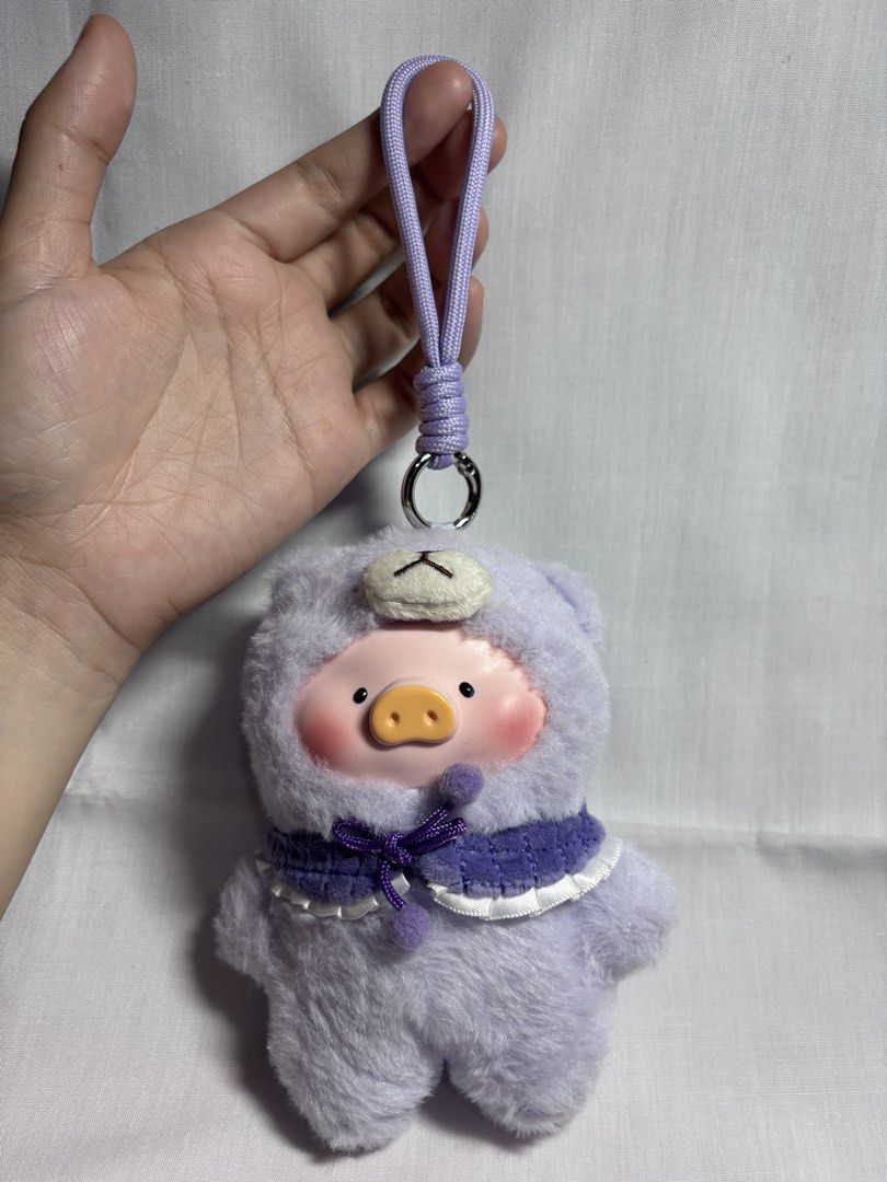 Lulu Purple Pig Plush Charm (Category: Plushies & Soft Toys) located in Sablan. Submitted by 21enygrace.ph (Listing ID 1462949997, Image 2). Description: - Adorable plush pig keychain - Features a cute purple hooded outfit - Decorated with a sweet bow and fluffy pom-poms - Made from soft and fluffy material - Ideal for personalizing bags, backpacks, or keys - A must-have accessory for lovers of all things cute!.
