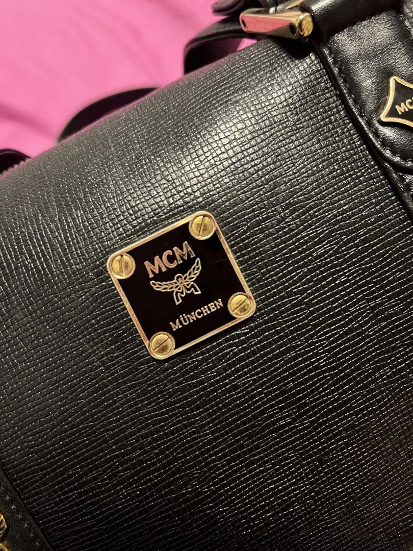 MCM München Black Leather Boston Bag (Category: Luxury Bags & Wallets) located in Bacoor. Submitted by lovedbybhellaiii (Listing ID 1457099005, Image 3). Description: - Authentic MCM Boston Bag - Textured Leather with Gold Hardware - Iconic MCM Logo Plaque and Emblems - Secure Zipper Closure - Comfortable Top Handles for Carrying - A Timeless and Classic Piece Just send me DMs for more detailed pic.