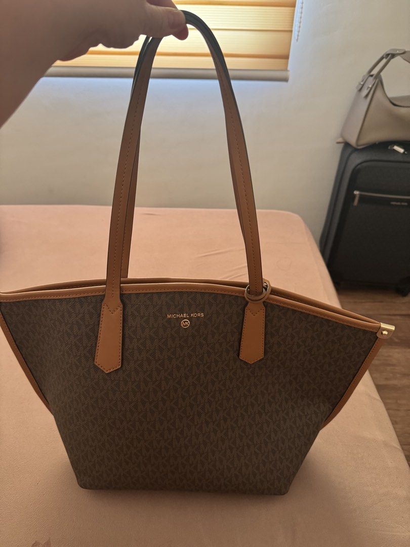 Michael Kors Monogram Tote Bag (Category: Luxury Bags & Wallets) located in Dasmarinas. Submitted by rinz0man (Listing ID 1462951332, Image 3). Description: - Classic Michael Kors tote bag - Signature MK monogram print - Tan leather trim and handles - Gold-tone hardware - Includes matching MK charm - Spacious interior, ideal for daily use.