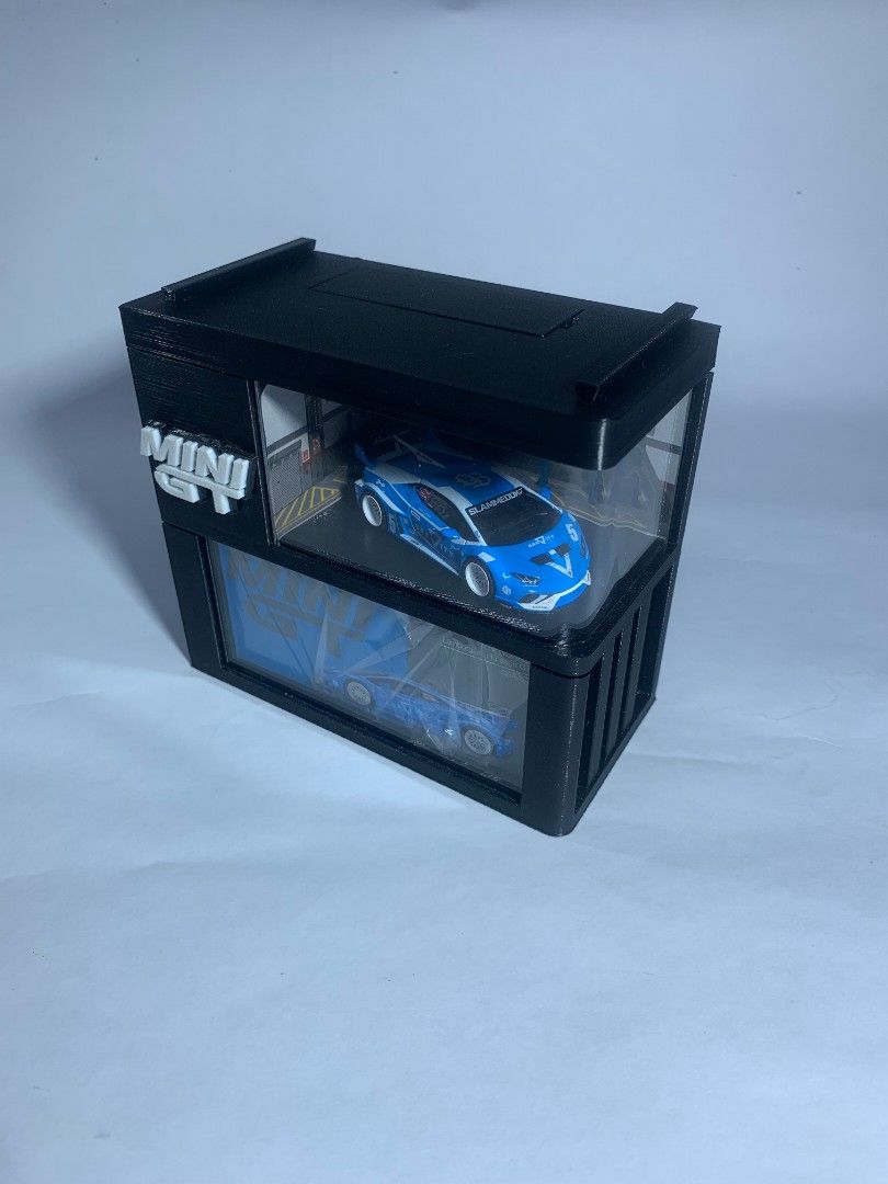 MINIGT DISPLAY CASE (Category: Designer & Blind Box Toys) located in Rizal. Submitted by project.streetwear (Listing ID 1463049640, Image 2). Description: What’s Inside the Box / Package Inclusions: 📦 1x Main Display Case (Diorama Garage Design with Original Box Slot) 🔲 1x Square Acrylic Panel ↪️ 1x Bended Acrylic Panel 🔋 2x AA Batteries (Included for lighting setup) 📌 2x Tack-It / Adhesive Pads (Para steady at di gumagalaw ang diecast.