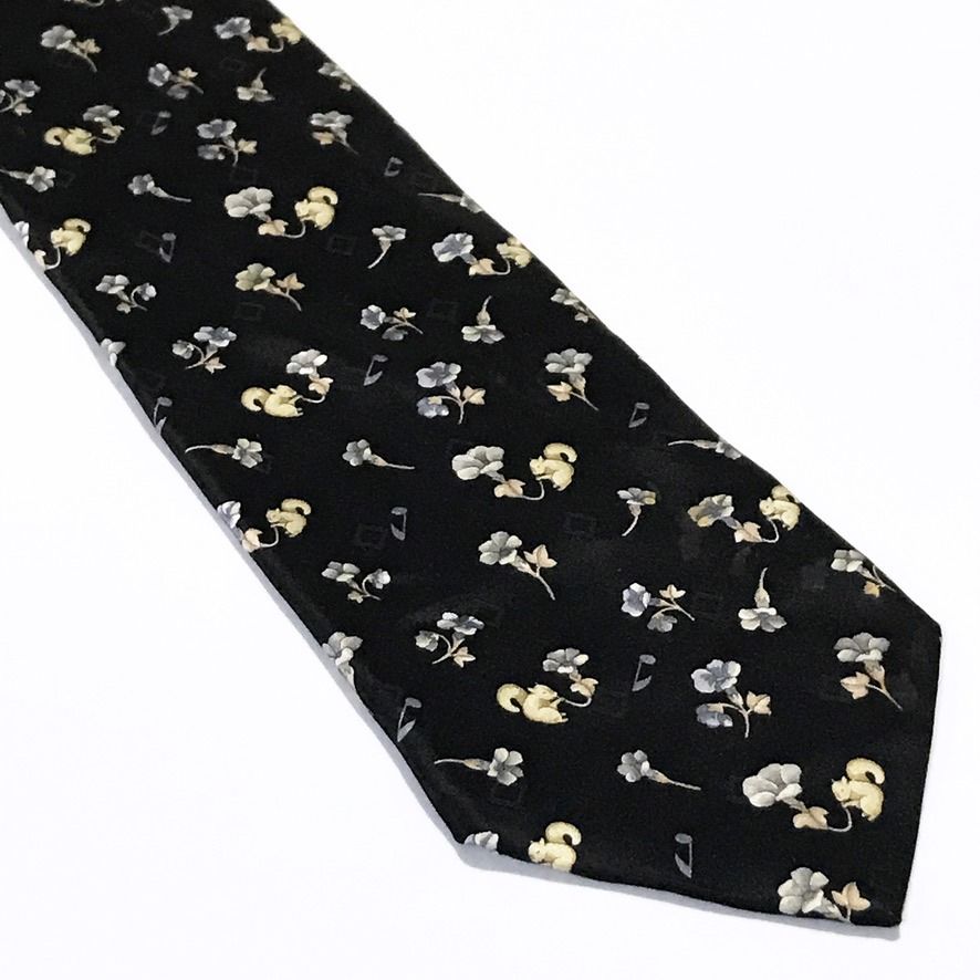 Nicole Miller Black Floral Pattern Neck Tie (Category: Ties) located in Taguig. Submitted by retrogaze (Listing ID 1463042067, Image 2). Description: This 100% silk necktie by Nicole Miller features a solid black base with a smooth, soft-sheen finish. The body displays a charming novelty pattern of delicate mini floral blossoms in periwinkle blue and cream, interspersed with small beige squirrels and floating musical notes. Brand Overview: Nicole