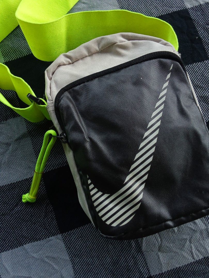 Nike Crossbody Bag Neon Strap (Category: Cross-body Bags) located in Manila. Submitted by timog_high_ice_v2 (Listing ID 1463114798, Image 2). Description: - Nike crossbody bag - Color: Black and grey body - Strap: Bright neon green, adjustable - Design: Large white Nike swoosh - Closure: Zipper with small loop pull - Functionality: Ideal for carrying essentials.