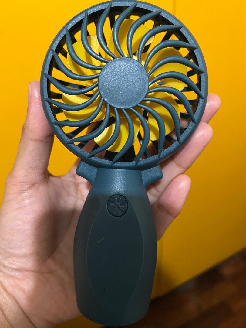 Portable Handheld Mini Fan (Category: Fans) located in Taguig. Submitted by prelovedaz_ (Listing ID 1463054118, Image 1). Description: - Compact handheld fan for personal cooling. - Simple button for power and speed control. - Features yellow blades and a dark grey body. - Easy to hold and operate for convenient use..