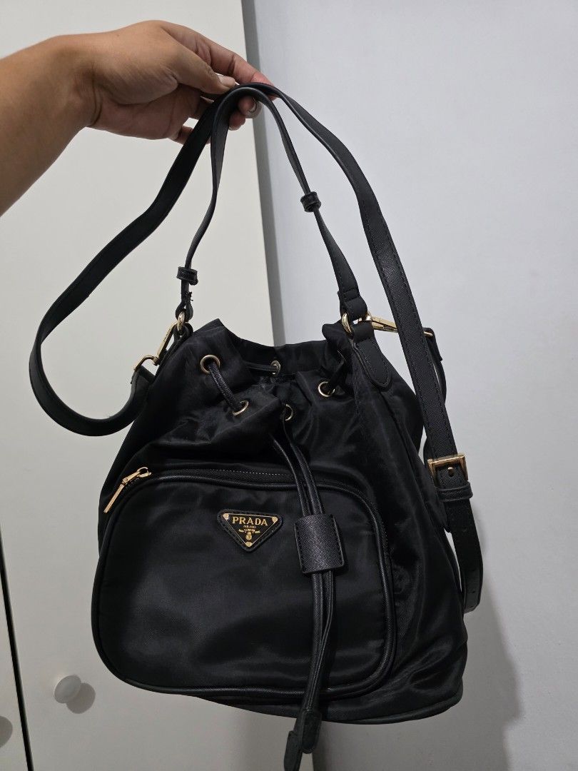 Prada Duet Nylon Bucket Bag (Category: Luxury Bags & Wallets) located in Manila. Submitted by decluttaro (Listing ID 1463076536, Image 2). Description: NGA Prada black nylon bag. Features drawstring closure, flap top, front zip pocket, and adjustable straps. Interior has Prada logo lining. Minor wear on inside lining near zipper as pictured..