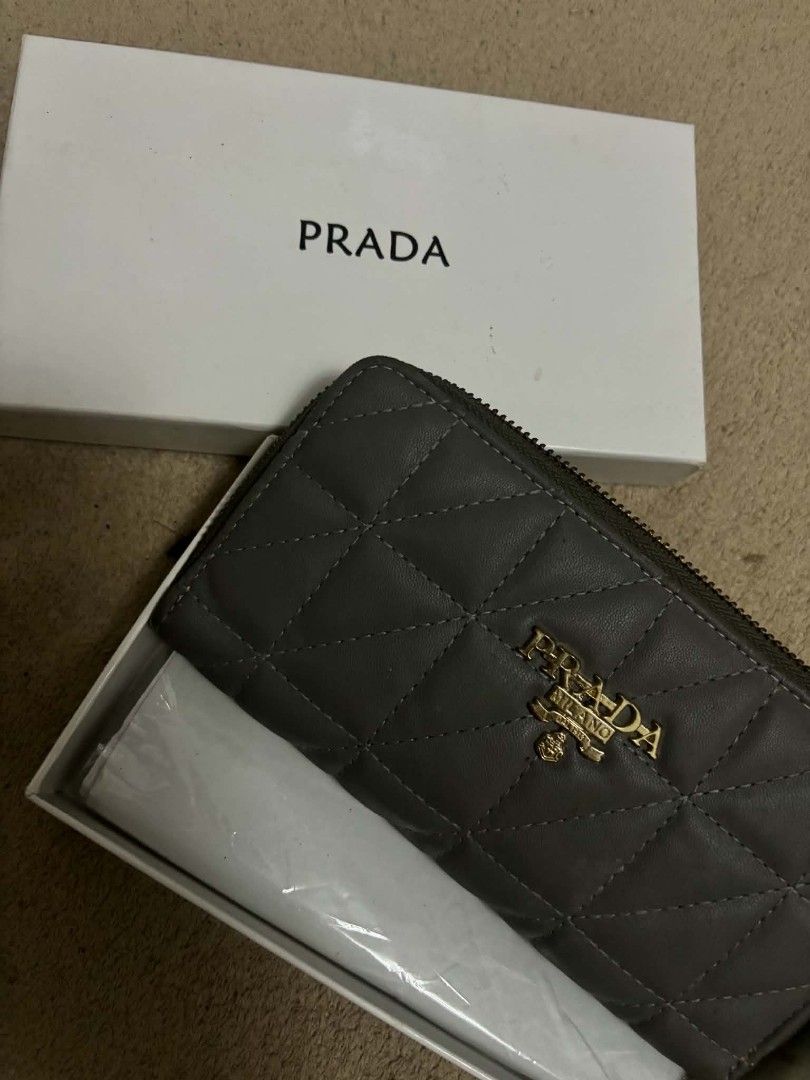 Prada Quilted Zip Around Wallet (Category: Luxury Bags & Wallets) located in Carmona. Submitted by myraprrzz (Listing ID 1462994434, Image 1). Description: - Authentic Prada wallet - Grey quilted leather with gold Prada logo - Comes with original box and packaging - Zip around closure - Multiple card slots and compartments - Ideal for everyday use.