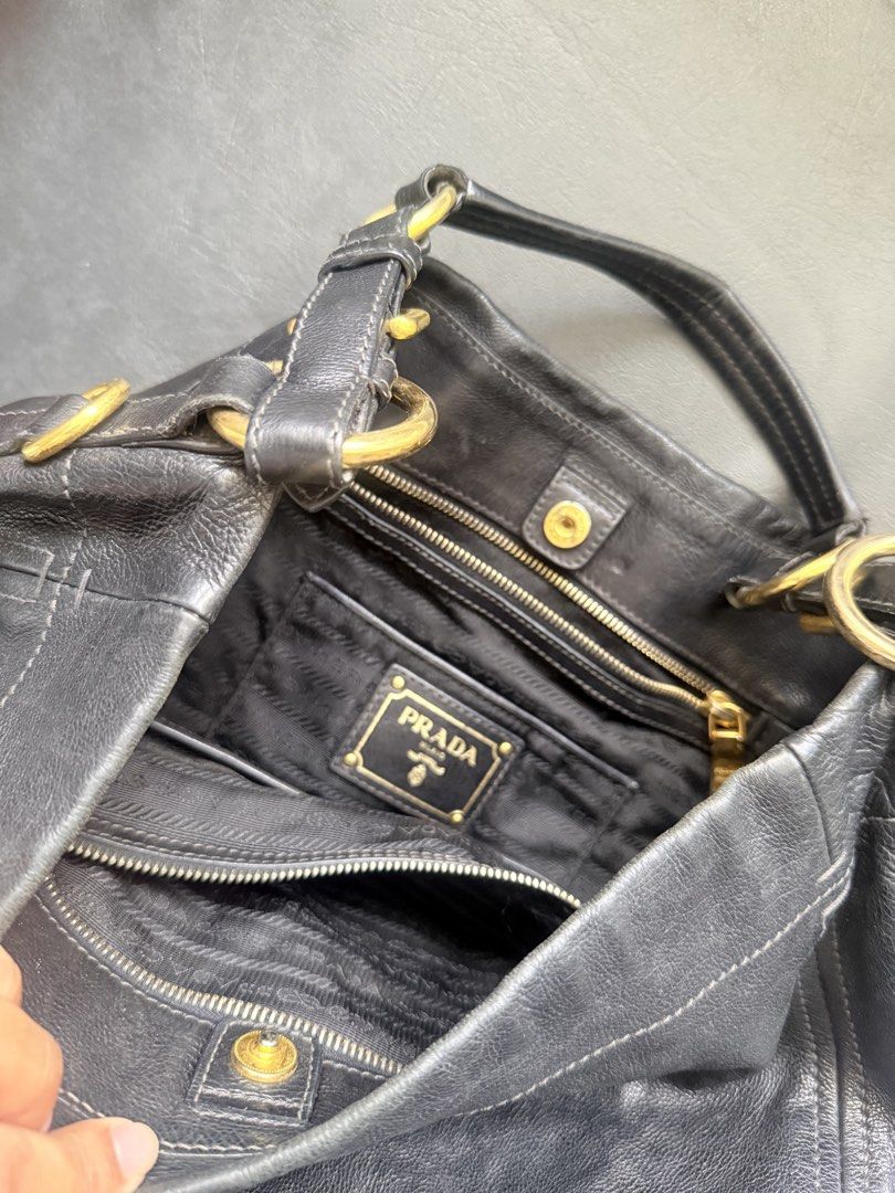 Prada Vitello Black Leather Hobo Shoulder Bag (Category: Luxury Bags & Wallets) located in Makati City. Submitted by quenniebee (Listing ID 1462896976, Image 3). Description: - Authentic Prada hobo bag - Black leather - Gold hardware details - Soft leather with a nice slouch - Interior with multiple compartments and zip pockets - Ideal everyday work bag, fits a laptop - Shows some signs of wear, but plenty of life left - Vintage, no white tag any