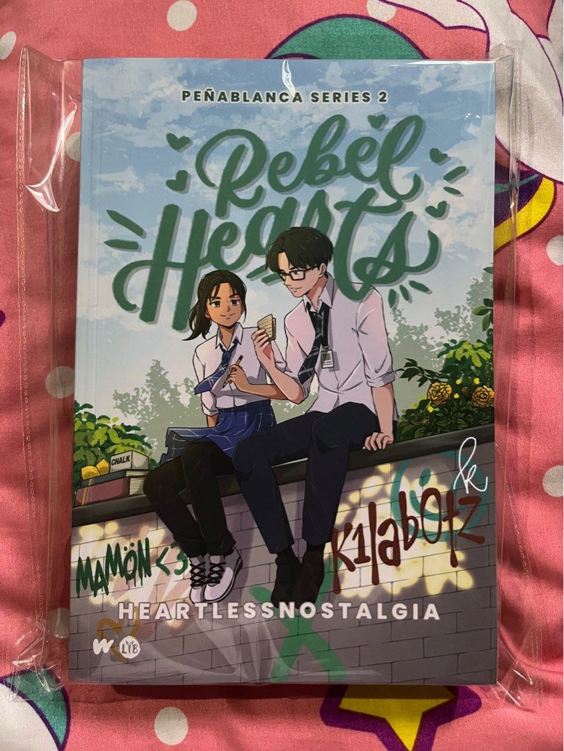 rebel hearts by heartlessnostalgia (Category: Storybooks) located in Naga. Submitted by .akaashi (Listing ID 1462989167, Image 1). Description: rebel hearts by heartlessnostalgia (chennie sandejas) - ₱350 (srp: 500) - bulky edition - signed - brand new, resealed with opp - just opened once to read sc - vvgc - with postcard, bookmark, and 3 photo cards loc: bicol mop: gcash .