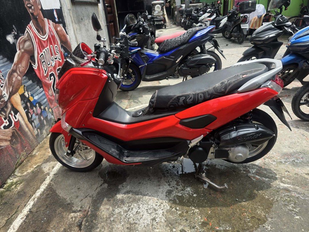 Red Yamaha NMAX (Category: Motorbikes for Sale) located in Manila. Submitted by polengg_whale (Listing ID 1462974387, Image 3). Description: Selling my red Yamaha NMAX. It has a carbon fiber windshield and a custom exhaust. The seat has a unique pattern. Great for city riding. Well maintained and runs smoothly. Ready for a new owner. Message me for more details or to arrange a viewing..