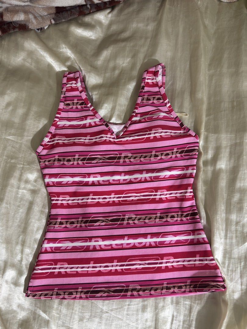 Reebok Pink Striped Tank Top (Category: Sleeveless) located in Legazpi City. Submitted by bouxloset (Listing ID 1463051215, Image 1). Description: - Cute pink and white striped Reebok tank top - All-over Reebok logo print - V-neck with racerback straps - Built-in bra lining for support - Ideal for workouts or casual wear.