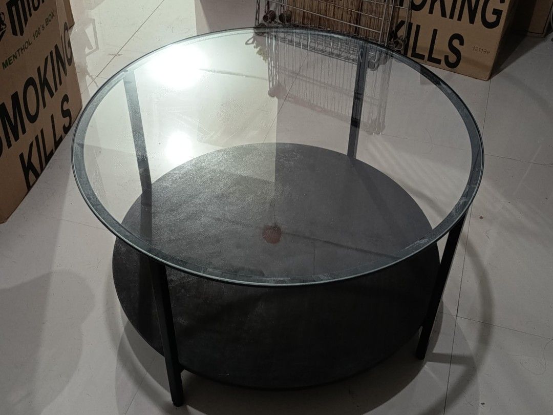 Round Glass Top Coffee Table with Black Metal Frame (Category: Tables & Sets) located in Muntinlupa City. Submitted by pitsipiya (Listing ID 1462977893, Image 3). Description: - Modern minimalist round coffee table - Features a clear glass top - Sturdy black metal frame - Includes a convenient lower shelf for extra storage - Ideal for living rooms and lounges - Easy to clean and maintain - Built for durability.