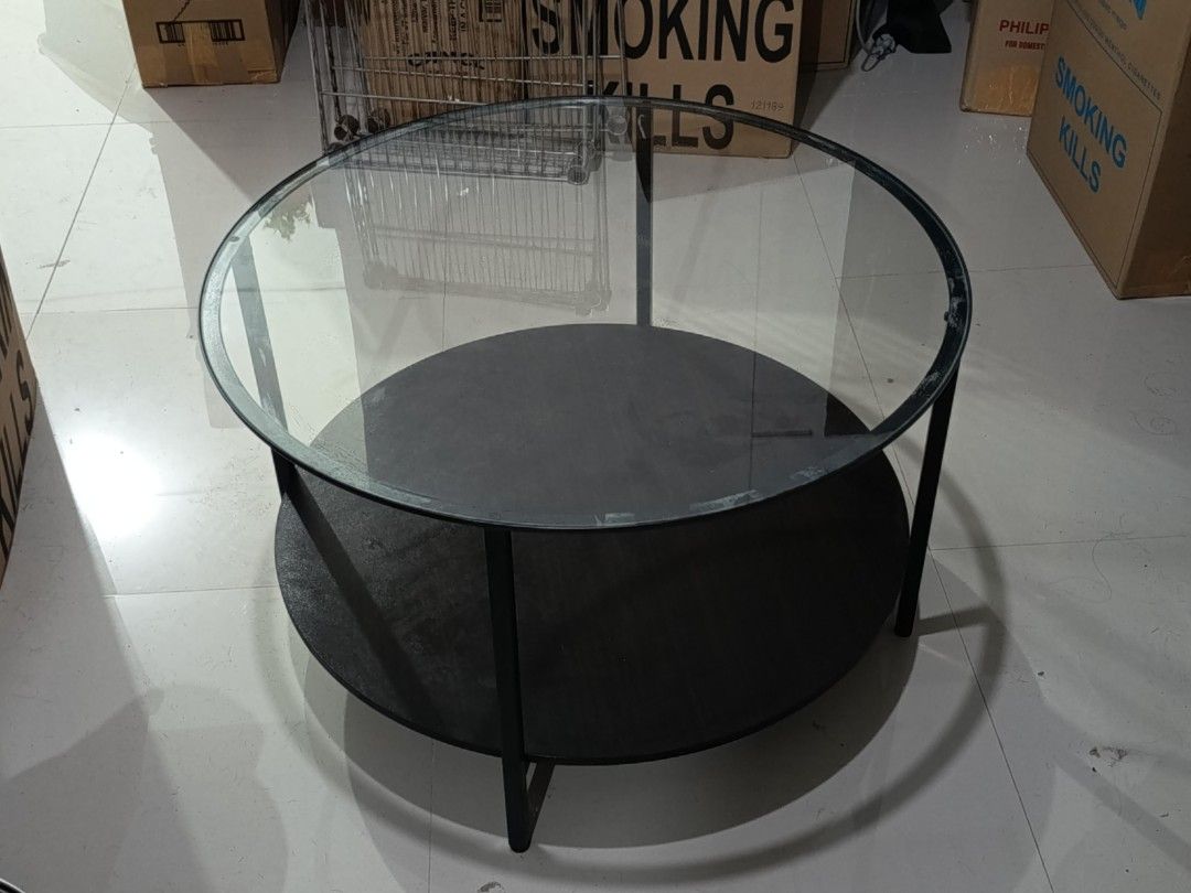 Round Glass Top Coffee Table with Black Metal Frame (Category: Tables & Sets) located in Muntinlupa City. Submitted by pitsipiya (Listing ID 1462977893, Image 2). Description: - Modern minimalist round coffee table - Features a clear glass top - Sturdy black metal frame - Includes a convenient lower shelf for extra storage - Ideal for living rooms and lounges - Easy to clean and maintain - Built for durability.