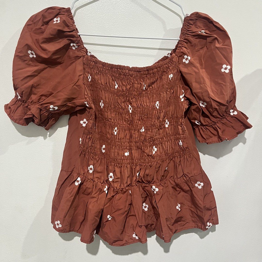 Rust Brown Puff Sleeve Smocked Floral Top (Category: Blouses) located in Quezon City. Submitted by shopnina (Listing ID 1462989896, Image 3). Description: - Cute top with a charming white floral print. - Features stylish puff sleeves and a flattering smocked bodice. - Elegant square neckline with a cute tie detail at the front. - Adorable ruffled hem and sleeve cuffs for a feminine touch. - Versatile style: looks great paired with jeans or a skir