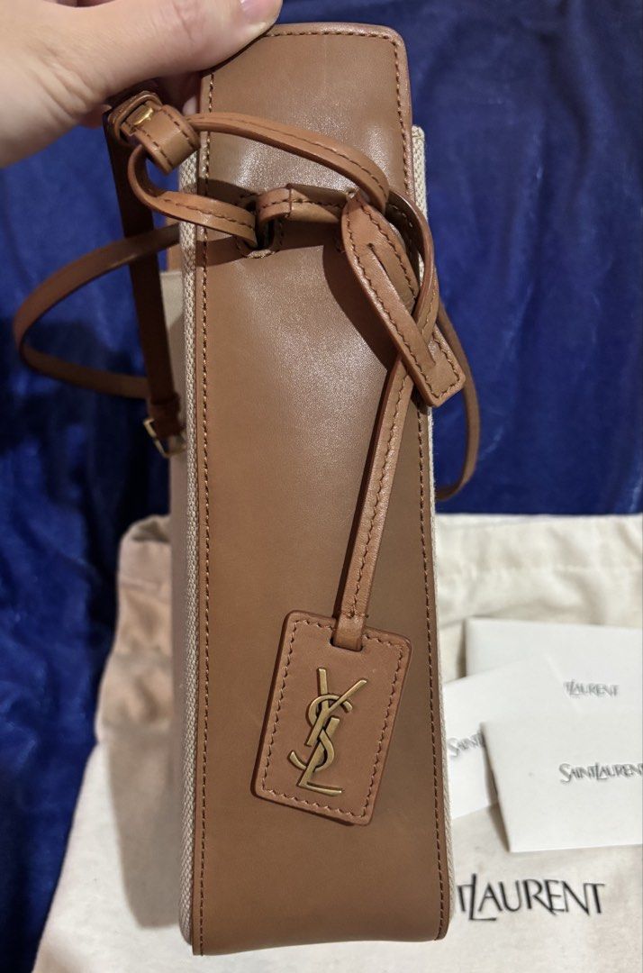 Authentic Saint Laurent Canvas & Leather Bucket Bag (Category: Luxury Bags & Wallets) located in Taytay. Submitted by cel127 (Listing ID 1462944545, Image 3). Description: - Authentic Saint Laurent bucket bag (10000000% authentic) - New model not vintage - Desert dust brick canvas with brown leather trim - Adjustable strap for crossbody (if petite) or shoulder wear - Iconic YSL logo charm - Includes dust bag and care cards - Negotiable for sure b