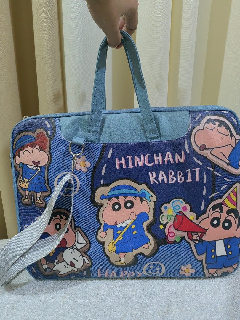 Shinchan "Hinchan Rabbit" Laptop Bag (Category: Laptop Bags & Sleeves) located in Makati City. Submitted by prelovedtreatedwithlove (Listing ID 1463002628, Image 1). Description: - Adorable Shinchan themed laptop bag - Durable blue denim-like material - Features various Shinchan character designs - Includes comfortable handles - Detachable shoulder strap for versatile carrying - Multiple internal compartments for organization - Built-in strap to 