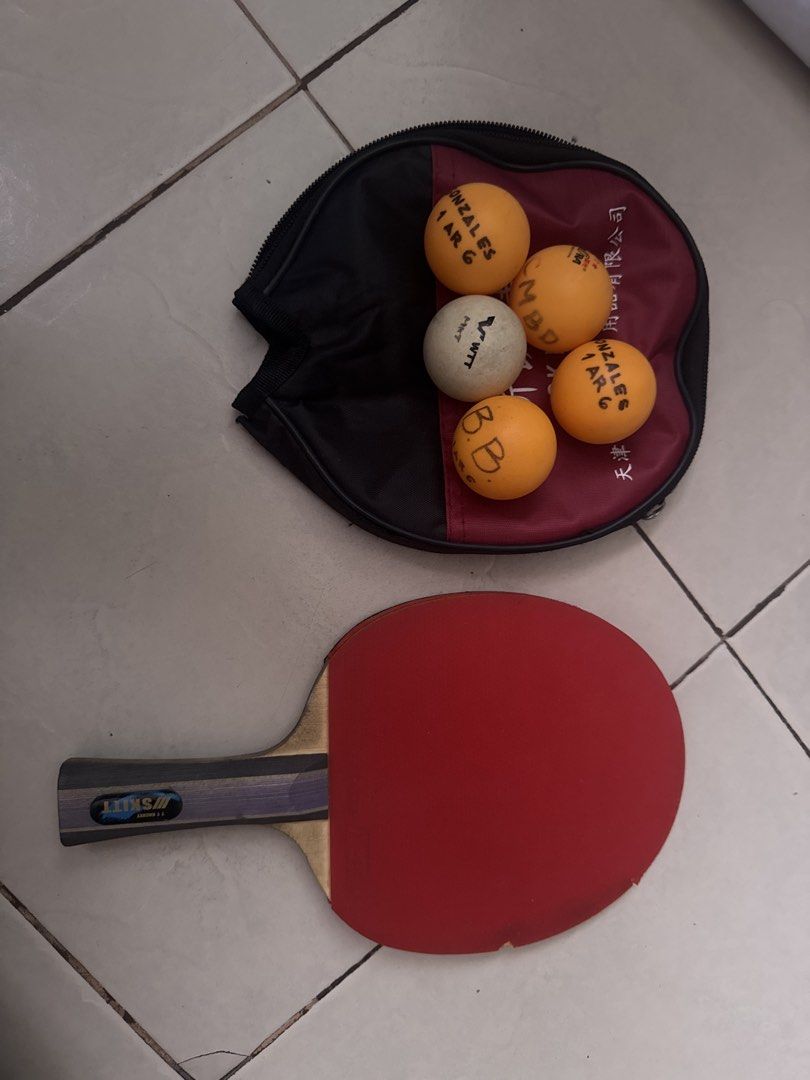 SKITT Table Tennis Racket with 5 Balls and Case (Category: Racket and Ball Sports) located in Manila. Submitted by rheyanamar23531 (Listing ID 1462906628, Image 1). Description: - SKITT table tennis racket - Comes with 5 balls (orange & white, some with names written) - Includes a black and red carrying case - Ideal for casual play or practice sessions - Racket features red rubber on one side.