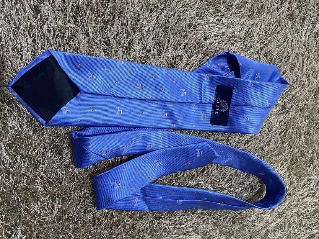 TAIYO Blue Silk Tie with Pattern (Category: Ties) located in Bulacan. Submitted by rich2545 (Listing ID 1462905236, Image 2). Description: - Brand: TAIYO - Material: Silk - Color: Blue - Design: Repeating pattern of horse-drawn carriages and small orange dots - Features: Subtle sheen - Occasion: Formal events, adding flair to outfits.