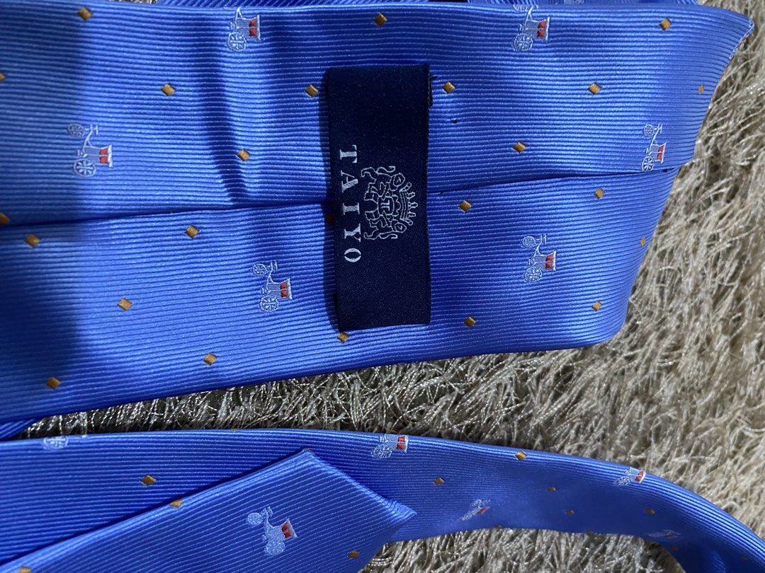 TAIYO Blue Silk Tie with Pattern (Category: Ties) located in Bulacan. Submitted by rich2545 (Listing ID 1462905236, Image 3). Description: - Brand: TAIYO - Material: Silk - Color: Blue - Design: Repeating pattern of horse-drawn carriages and small orange dots - Features: Subtle sheen - Occasion: Formal events, adding flair to outfits.
