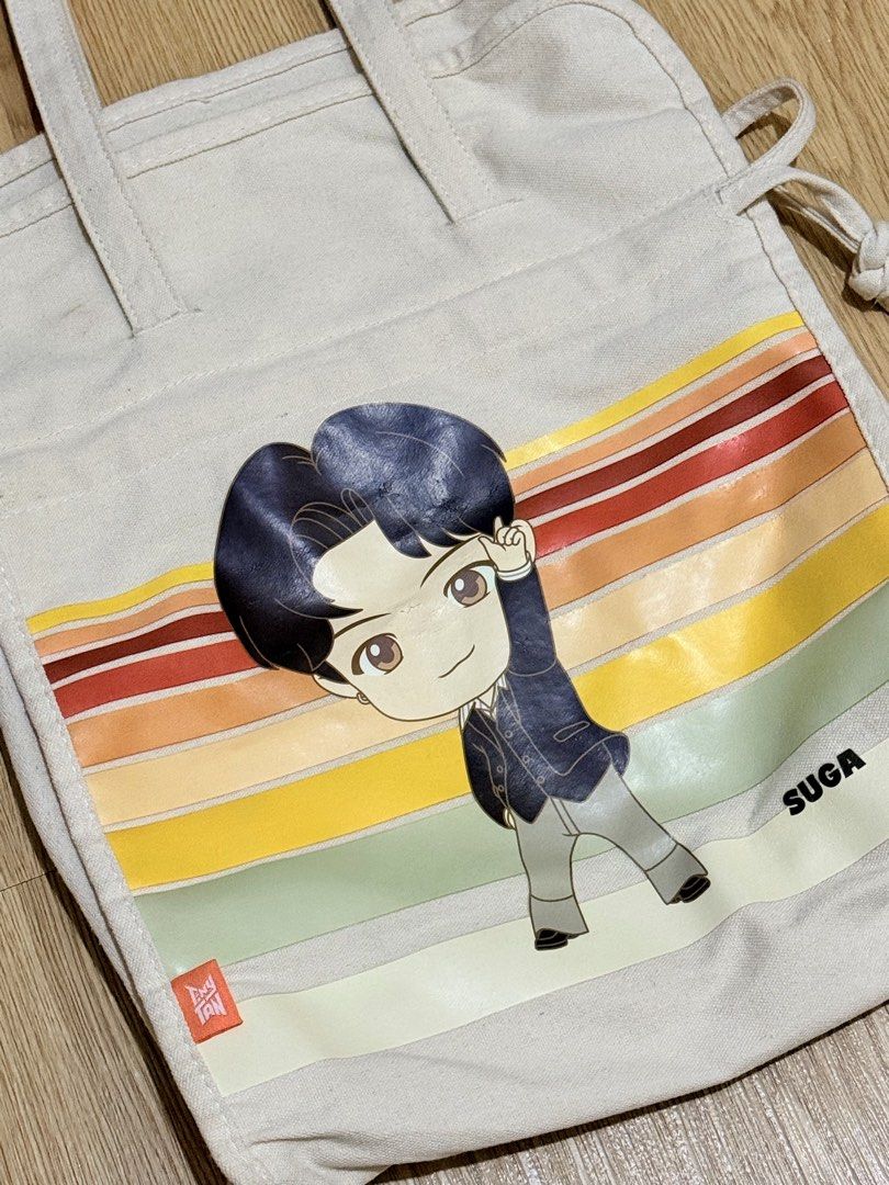 TinyTAN Canvas Tote Bag - Suga (Category: Tote Bags) located in San Pedro. Submitted by itsminaxvii (Listing ID 1462826570, Image 3). Description: - Adorable TinyTAN character design - Vibrant, colorful striped background - Features a small orange 'TinyTAN' tag - Ideal for everyday use - Perfect as a fan collectible.
