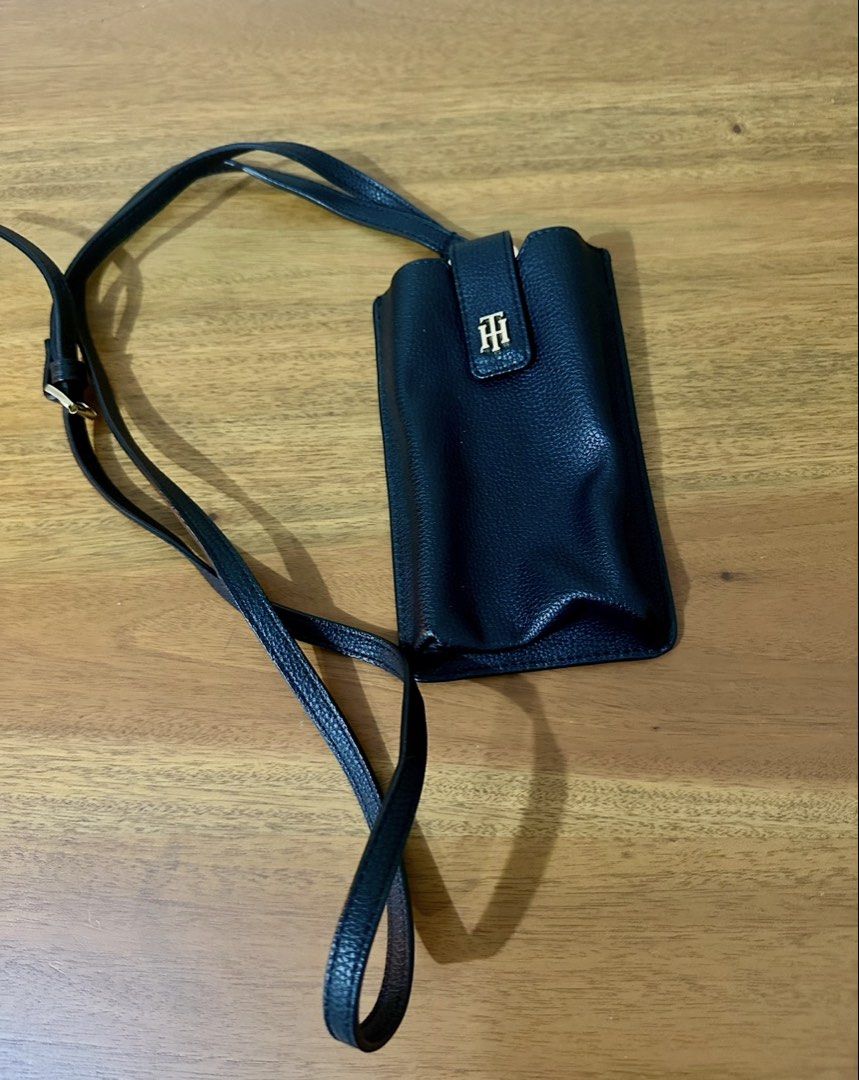 Tommy Hilfiger Black Leather Phone Pouch with Strap (Category: Purses & Pouches) located in Quezon City. Submitted by decluttering.mommy (Listing ID 1463003528, Image 3). Description: - Genuine black leather phone pouch by Tommy Hilfiger - Adjustable long strap for comfortable wear - Iconic Tommy Hilfiger logo prominently displayed on the front - Convenient card slot on the back for essentials - Brand new with original tag attached - Ideal for ke