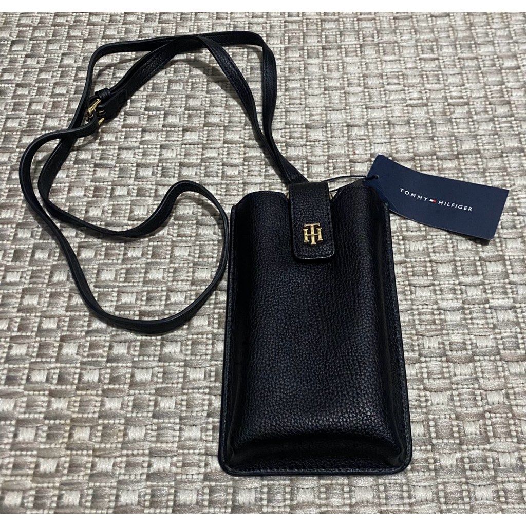 Tommy Hilfiger Black Leather Phone Pouch with Strap (Category: Purses & Pouches) located in Quezon City. Submitted by decluttering.mommy (Listing ID 1463003528, Image 1). Description: - Genuine black leather phone pouch by Tommy Hilfiger - Adjustable long strap for comfortable wear - Iconic Tommy Hilfiger logo prominently displayed on the front - Convenient card slot on the back for essentials - Brand new with original tag attached - Ideal for ke