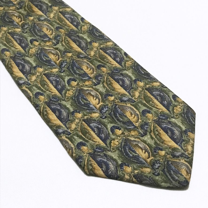 Van Heusen Vintage Leaf Pattern Sage Green Neck Tie (Category: Ties) located in Taguig. Submitted by retrogaze (Listing ID 1462933418, Image 2). Description: This vintage 100% silk necktie by Van Heusen features a sage olive green base woven with a ribbed twill texture. The body displays a dense, tapestry-inspired repeating ornamental leaf pattern, featuring split acanthus motifs in muted gold, ochre tan, and slate navy blue. Brand Overview: Foun