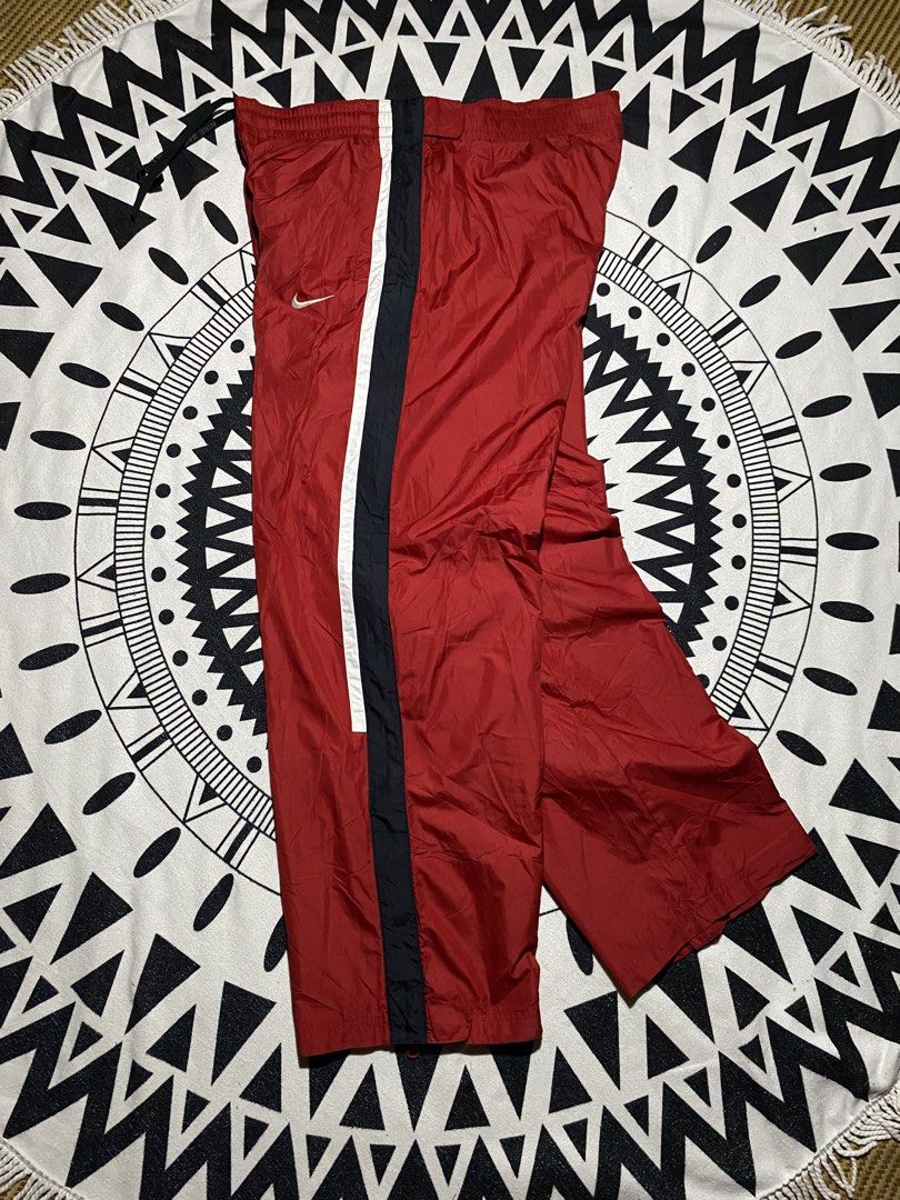 Vintage Nike Red Track Pants Snap Button Sides (Category: Joggers) located in Badiangan. Submitted by iralorana.thrift (Listing ID 1462930741, Image 3). Description: - Classic red Nike track pants - Iconic Nike swoosh logo - Side snap buttons for easy wear - Elastic waistband with drawstring for adjustable fit - Side stripe detail for a sporty look - Ideal for sports or casual outfits.