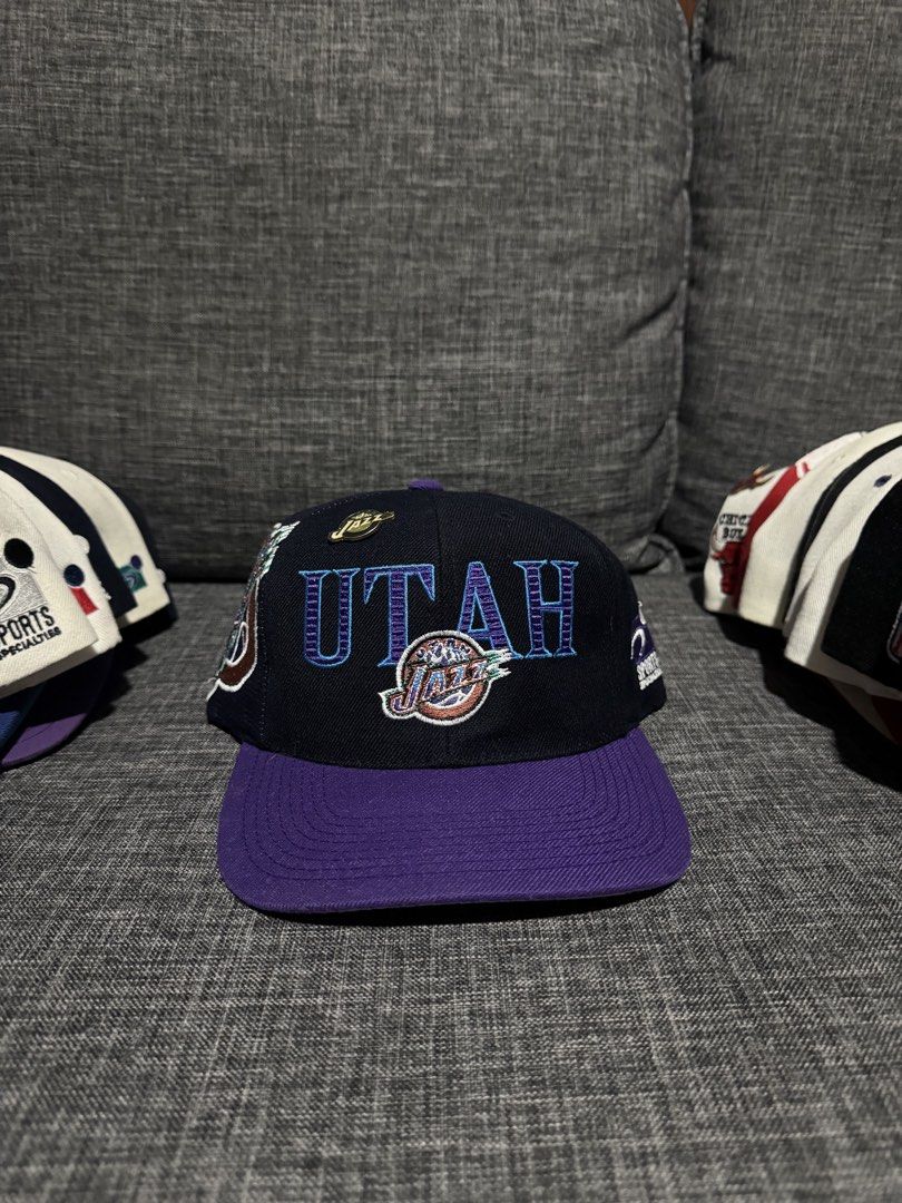 Vintage Utah Jazz NBA Lazer Cap (Category: Caps & Hats) located in Solano. Submitted by Hustle.Everyday (Listing ID 1463038080, Image 1). Description: - Black and purple Utah Jazz snapback cap - Features embroidered 'UTAH' and the Jazz logo - Adjustable snapback for a comfortable fit - Ideal for any Utah Jazz enthusiast.