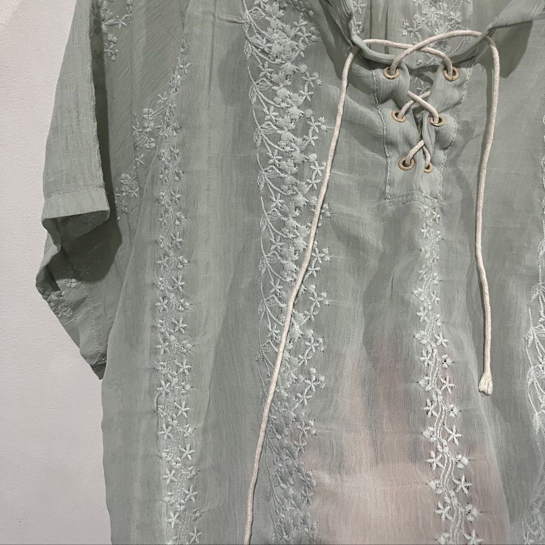 Vivid & Co. Boho Embroidered Lace-Up Blouse (Category: Blouses) located in Quezon City. Submitted by shopnina (Listing ID 1462988989, Image 2). Description: - Light green sheer blouse - Delicate white floral embroidery - Short sleeves - Lace-up neckline with gold eyelets - Gathered yoke at the back - Lightweight and airy fabric - Versatile for casual or dressed-up looks fits Med-Large.