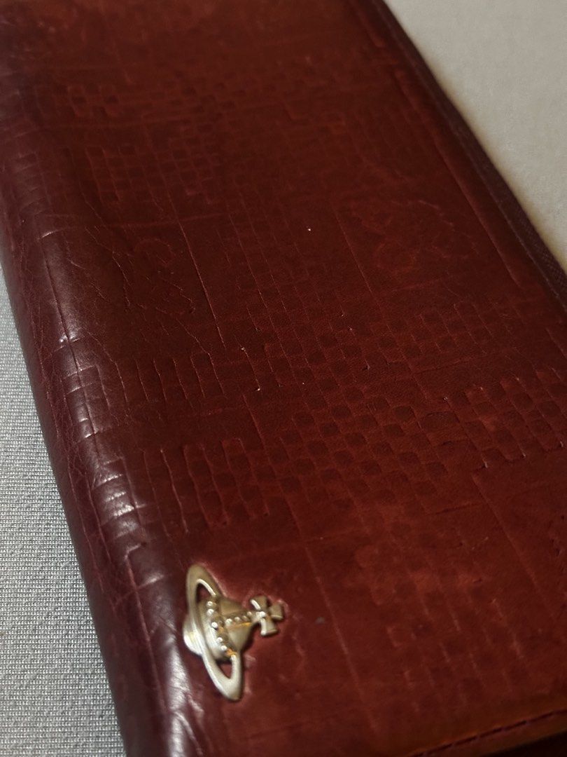 Vivienne Westwood Leather Long Wallet (Category: Luxury Bags & Wallets) located in Manila. Submitted by declutterthisandthat (Listing ID 1462889623, Image 3). Description: - Vivienne Westwood long wallet - Rich burgundy red leather - Elegant embossed pattern - Iconic orb logo on the front - Spacious interior with multiple card slots and compartments - Secure zipper closure - Perfect for keeping your essentials organized.