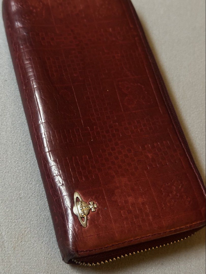 Vivienne Westwood Leather Long Wallet (Category: Luxury Bags & Wallets) located in Manila. Submitted by declutterthisandthat (Listing ID 1462889623, Image 1). Description: - Vivienne Westwood long wallet - Rich burgundy red leather - Elegant embossed pattern - Iconic orb logo on the front - Spacious interior with multiple card slots and compartments - Secure zipper closure - Perfect for keeping your essentials organized.