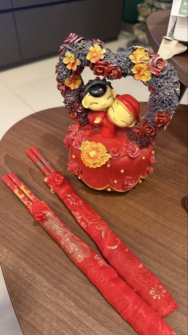 Wedding stuff (Category: Occasions & Party Supplies) located in Singapore. Submitted by geminitoh (Listing ID 1463017621, Image 1). Description: - Musical Decorative figurine of a couple embracing within a heart-shaped frame. - Adorned with beautiful flowers. - Includes a pair of red chopsticks. - Chopsticks come in matching decorative sleeves with intricate gold patterns. - Vibrant red base for the figurine with floral accents. - Ideal as a gift