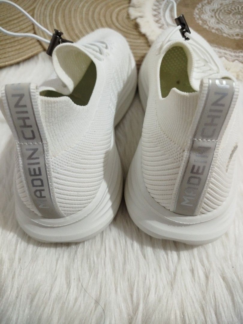 White Knit Sneakers with Elastic Laces (Category: Sneakers) located in Quezon City. Submitted by plus4lessshop (Listing ID 1462918407, Image 3). Description: - White knit sneakers - Easy slip-on style with elastic laces and toggle - Breathable knit upper with perforated details - "MADE IN CHIN" stamped on heel tab - Comfortable and casual design.