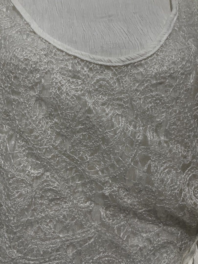 White Lace Overlay Sleeveless Tie-Side Top (Category: Sleeveless) located in Tabuk. Submitted by zenwolf-1867 (Listing ID 1463052930, Image 2). Description: - White sleeveless top - Delicate lace overlay with intricate pattern - Crinkled texture on inner layer - Tie-side closure - Lightweight and airy - Versatile: great for layering or wearing alone.