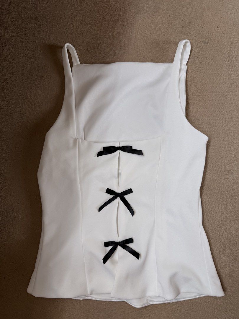 White Square Neck Top with Black Bow Detail (Category: Blouses) located in San Juan City. Submitted by elkaytea27 (Listing ID 1462947323, Image 1). Description: - White square neck top - Corset-style back with 3 black ribbon bows - Sleeveless with thin straps - Fitted silhouette - Perfect for dressing up or down.