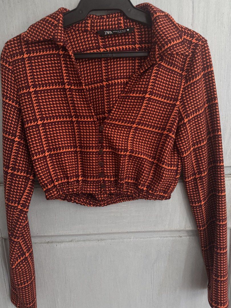 ZARA Cropped Shirt Orange Houndstooth Pattern Long Sleeve (Category: Longsleeves) located in Manila. Submitted by decluterthings888 (Listing ID 1462950050, Image 1). Description: - Zara cropped shirt - Orange and dark red houndstooth pattern - Long sleeves - Collared neckline - Button-up front - Elasticated hem - Estimated size: XS.