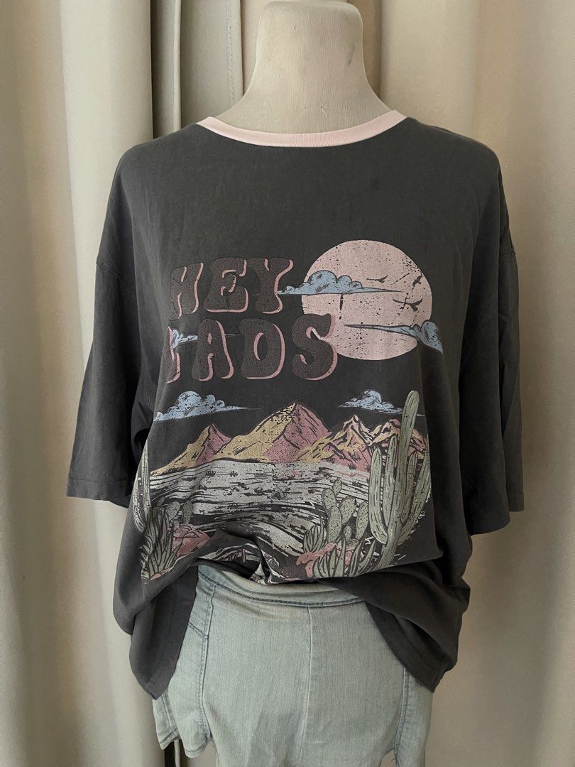 acidwash Gray-pink vintagey (Category: Shirts) located in Cainta. Submitted by zlove111 (Listing ID 1463178679, Image 2). Description: - Cool grey oversized graphic t-shirt - Features a desert landscape design with mountains, cacti, and a moon - Text reads 'HEY LADS' and 'DESERT ADVENTURE' - Unique light pink trim around the neckline - Oversized fit for a relaxed, casual style - Ideal for everyday wear and adding a touch of adventure to your look
