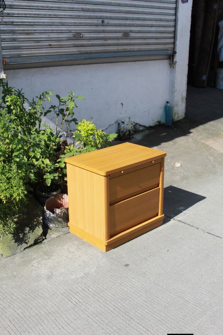 Bedside Table (Category: Tables & Sets) located in Meycauayan. Submitted by marygracecasimiro (Listing ID 1463260437, Image 3). Description: Modern Wooden Bedside Table with Pull-Out Tray Two spacious drawers, a convenient pull-out tray, rounded edges and a sturdy plinth base. Finished in a light honey-oak tone, perfect for bedrooms, living rooms or compact spaces L:23 ¾ • W:15 ¾ • H:22 ¼ inches 5,000 pesos only🩷🧡.