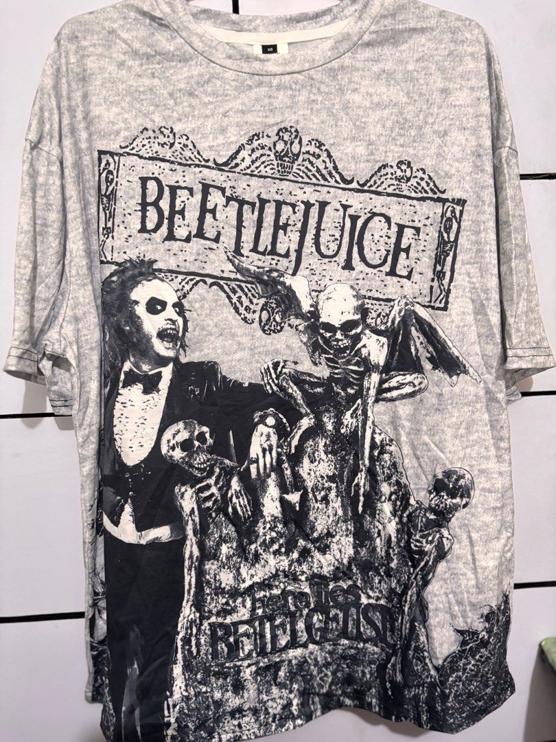 Beetlejuice Graphic T-Shirt (Category: Tshirts & Polo Shirts ) located in Bacoor. Submitted by dangeusebio1515 (Listing ID 1463325480, Image 1). Description: - Grey graphic t-shirt - Features Beetlejuice and spooky skeletons - Unique marbled fabric effect - Estimated size: XS - Ideal for Beetlejuice fans.