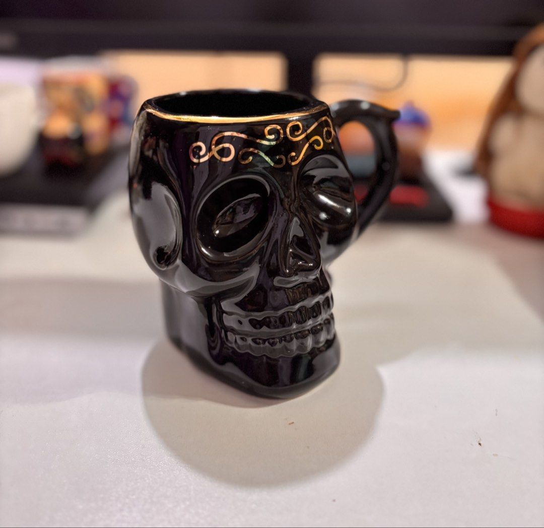 Black Skull Mug with Gold Swirls (Category: Coffee & Tea Tableware) located in Bacoor. Submitted by dangeusebio1515 (Listing ID 1460907757, Image 2). Description: - Unique black skull design - Elegant gold swirls on the rim - Ideal for coffee, tea, or any drink - Perfect gift for gothic or spooky decor lovers - Dishwasher and microwave safe - Comfortable handle for easy grip.