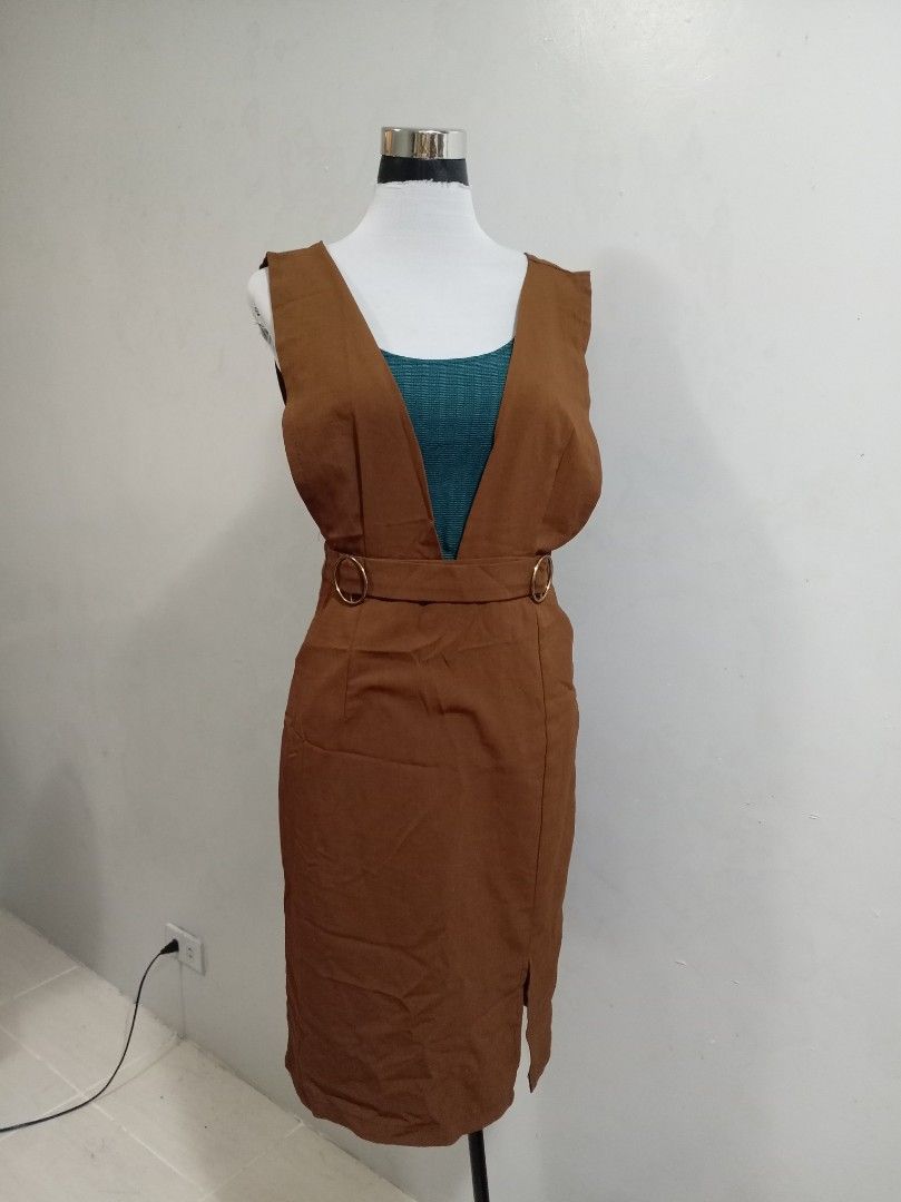Brown Pinafore rompers (Category: Jumpsuits) located in Paranaque City. Submitted by janella11 (Listing ID 1463180566, Image 2). Description: - Stylish brown pinafore - Deep V-neckline - Belt detail with gold rings at the waist - Skirt with a side slit - Versatile for casual or semi-formal occasions.