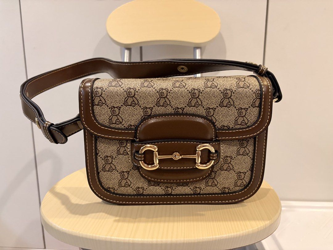 Brown Teddy Bear Print Shoulder Bag with Gold Buckle (Category: Shoulder Bags) located in Manila. Submitted by jonahgmzn (Listing ID 1463226421, Image 1). Description: - Cute brown shoulder bag - Adorable teddy bear print - Classic gold buckle closure - Front flap design - Interior zippered compartments for organization - Adjustable strap for comfortable wear - Versatile for everyday use or nights out - minor storage flaws.