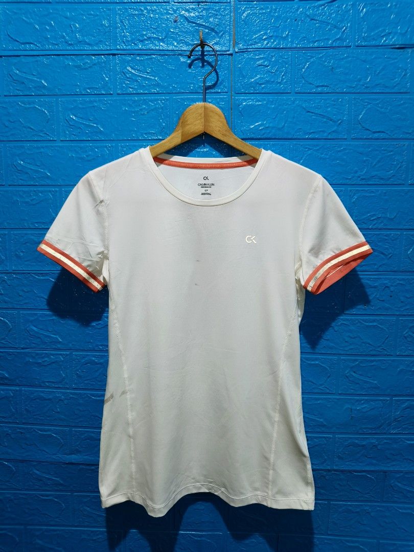 Calvin Klein Performance White T-shirt Size S (Category: Activewear) located in Davao. Submitted by vndrgd (Listing ID 1463119946, Image 2). Description: - White Calvin Klein Performance T-shirt - Size: S - Orange trim on sleeves and neckline - Measurements: 17" width, 24" length - Minor faint marks on front and near hem - Perfect for workouts or casual wear.